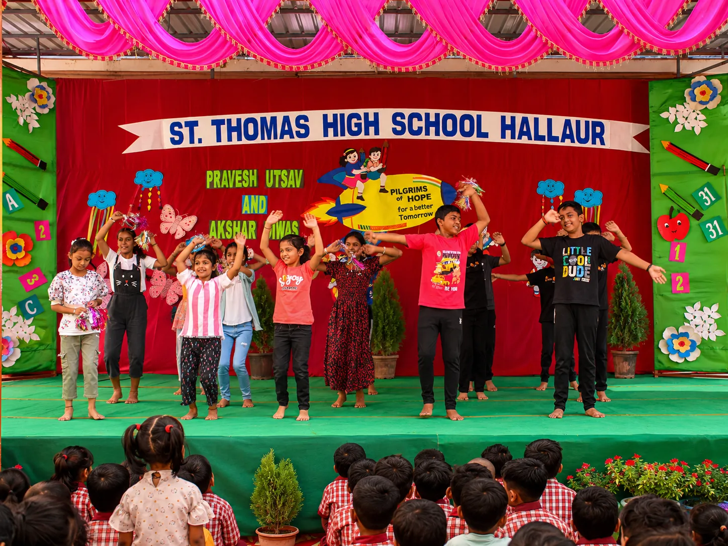 Pupils performing a group dance on stage at the Pravesh Utsav and Akshar Diwas celebration